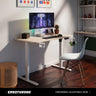 Ergonomic adjustable desk setup with a computer monitor, keyboard, and chair in a home office.